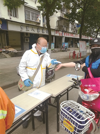 4月上旬，朱江雄（左）在武汉市汉阳区琴断口街道桃花岛社区旺达小区封控点测量体温。程慧朋 摄