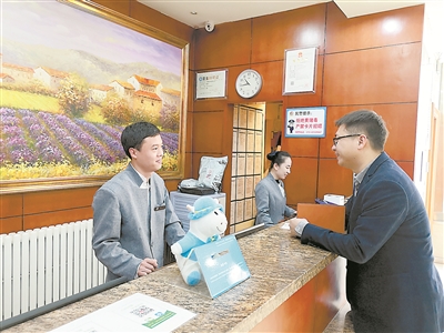 北京市西城区某快捷酒店的前台接待曹健涛(左一)表示,他所在的快捷酒店成为越来越多来京出差干部的入住选择,明显感觉许多干部的节约意识增强了,会盘算着帮公家省钱了。