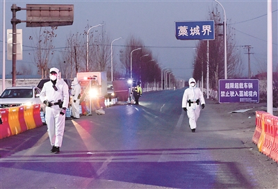 1月5日,在河北省303省道石家庄市藁城区界疫情检测点,工作人员对过往车辆进行仔细检测,同时保证道路正常通行。赵杰 摄