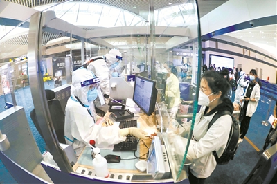 中秋期间,山东省出入境边防检查总站青岛机场出入境边防检查站加强值班备勤警力,利用“大数据”强化对入境人员的防控风险动态评估,全力做好节日期间疫情防控和口岸管控等工作。图为检查站民警为旅客办理通关手续。 (图片来源:人民视觉)