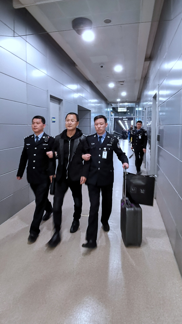 袁国方在机场边检人员的带领下离开飞机从登机口出来(胡高生 摄)