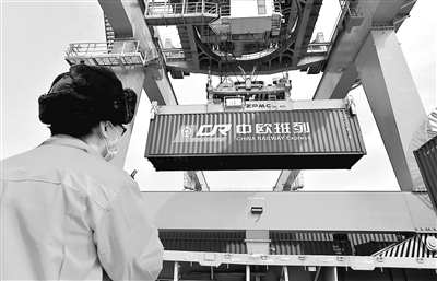 3月11日,一列满载服装、电子配件、电器等50车货品的列车驶出西安新筑车站,开往德国曼海姆,标志着2020年中欧班列(西安)去程班列发送车数突破1万车。图为工人在西安新筑车站货场指挥吊运中欧班列集装箱。 新华社发(唐振江 摄)