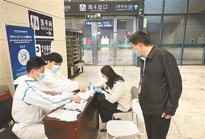 图为4月7日,张圣新(右一)正在武汉火车站检查返汉人员信息登记工作。王昆 摄