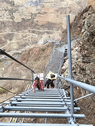 在搬下山之前,阿土列尔村村民只能通过宽1.5米、总长度2.8公里的钢铁“天梯”进出。图为村民们背着背篓攀爬钢梯。 新华社记者 薛晨 摄