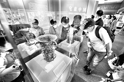 距今3000多年的青铜何尊,器内底部有122字铭文。其中的“宅兹中国”,是关于“中国”一词最早的文字记载,彰显了中华文化源远流长的独特魅力。图为2020年8月18日,观众在国家博物馆“宅兹中国——宝鸡出土青铜器与金文精华”展上观看展出的何尊。 (图片来源:视觉中国)