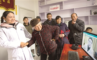 地处大别山腹地的安徽省金寨县大湾村率先在全省开通5G远程医疗会诊功能,住在深山的农村群众可及时享受到优质的医疗服务。图为该村村民在村医的帮助下向5G远程医疗会诊专家讲述病情。新华社发(陈力 摄)