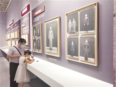 图为“民族复兴的百年旗帜——中国历史研究院征集海外中共珍稀文献展”现场,小观众在革命先烈遗照前写下参观感言。 本报记者 聂新鑫 摄
