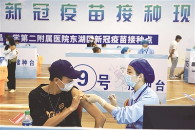 近日,在江西省体育馆方舱接种点,南昌大学第二附属医院的医护人员在给大学生接种新冠疫苗。新华社记者 万象 摄