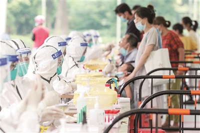 图为医护人员在江苏省扬州市邗江区邗江中学检测点,为居民进行核酸采样。(图片来源:视觉中国)