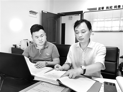 图为肖鹰(右)正在查阅相关案件资料。
