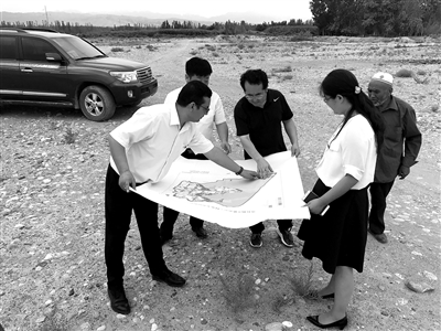 阿迪力·艾力(中)同设计规划人员现场勘察林果基地。(资料图片)