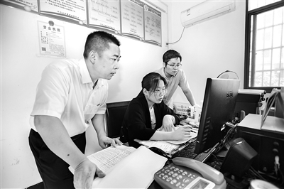 图为施昌年(左)在办案中调阅相关资料。